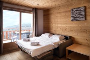 a bed in a room with a large window at Dormio Resort Les Portes du Grand Massif in Flaine +35 photos
