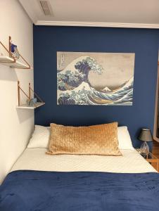 a bedroom with a blue wall with a painting of a wave at Alicante airport and beach in El Alted