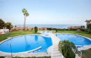 Una gran piscina en un resort con el océano al fondo. en Penthouse La Roca, en La Herradura