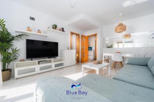 Una sala de estar con un sofá azul y un televisor en Penthouse La Roca, en La Herradura