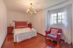 a bedroom with a bed and a chair and a chandelier at YourHouse A Casa Dos Cregos in Fonteita