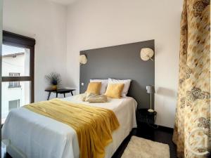 una camera da letto con un letto con una coperta gialla sopra di Maison de village - Haut de Gamme avec patio a Thuir