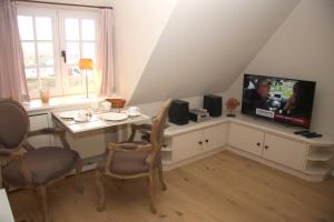 sala de estar con TV, mesa y sillas en Apartmenthaus Witthüs, en Wenningstedt
