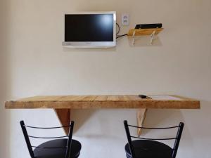 TV con mesa de madera y 2 sillas en Pousada Rota da Serra, en Munhoz