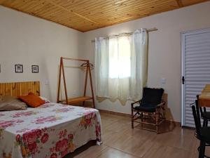 1 dormitorio con 1 cama, 1 silla y 1 ventana en Pousada Rota da Serra, en Munhoz