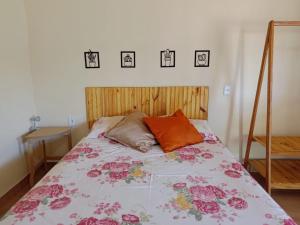 Un dormitorio con una cama con flores rosas. en Pousada Rota da Serra, en Munhoz