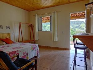 1 dormitorio con 1 cama, 1 mesa y 2 ventanas en Pousada Rota da Serra, en Munhoz