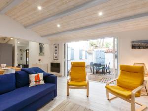 sala de estar con sofá azul y 2 sillas amarillas en Holiday Home Les Trémières by Interhome, en La Palmyre