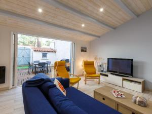 Una sala de estar con un sofá azul y un televisor. en Holiday Home Les Trémières by Interhome, en La Palmyre