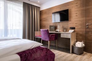 a bedroom with a bed and a desk and a tv at Hotel Sonnegg in Saalbach Hinterglemm