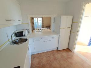 イスラ・カネラにあるURBANIZACIÓN SAN BRUNO II 2 DORM EN 1º PLANTAのシンクと冷蔵庫のある小さなキッチン +9枚の写真