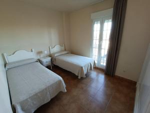 イスラ・カネラにあるURBANIZACIÓN SAN BRUNO II 2 DORM EN 1º PLANTAのベッド2台と窓のある寝室