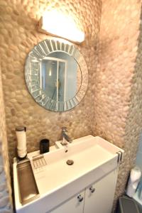 La salle de bains est pourvue d'un lavabo blanc et d'un miroir. dans l'établissement Appartement avec vue 180 sur le Lac Léman, à Thonon-les-Bains