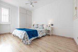 1 dormitorio blanco con 1 cama con manta azul en Bettatur Apartaments Via Imperi Romà, en Tarragona