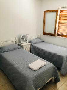 a room with two beds and a tv and a window at Hermosa y Amplia Casa Familiar en Alta Gracia in Alta Gracia