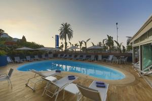 a swimming pool with tables and chairs next to a building at Hotel Napoléon in Menton