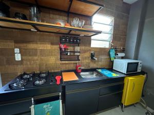 uma pequena cozinha com fogão e micro-ondas em Confortável Kitinete Duplex em Fortaleza