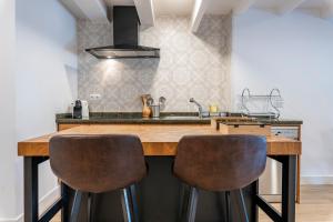 une cuisine avec un comptoir en bois et deux tabourets de bar dans l'établissement Bettatur Apartaments Via Imperi Romà, à Tarragone