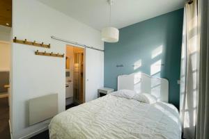 - une chambre avec un lit blanc et un mur bleu dans l'établissement Appartment in a 16th-century castle, à La Rochelle