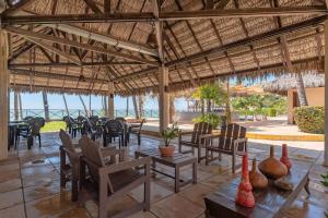 patio ze stołami i krzesłami pod słomianym dachem w obiekcie Eco Paradise #101 - Apê em Cumbuco por Carpediem w mieście Cumbuco