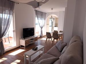Una sala de estar con un sofá, un televisor y una mesa. en Ático Bella Vista, en Cómpeta