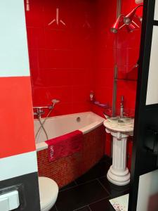 een rode badkamer met een bad en een wastafel bij Apartament Brzozowa in Chorzów