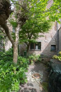 een tuin met twee bomen voor een bakstenen gebouw bij De Wijngaard in Gent