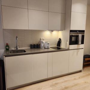a white kitchen with a sink and a microwave at Nice Apartment Close to Ilford Station , NETFLIX AND WI-FI FREE in Ilford