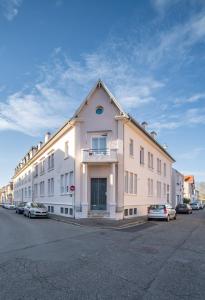 un grand bâtiment blanc avec des voitures garées dans un parking dans l'établissement Le Bardin - Grand appartement design, parking gratuit, à Vichy