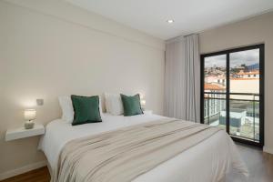a white bedroom with a large bed and a window at Santa Luzia III by An Island Apart in Funchal