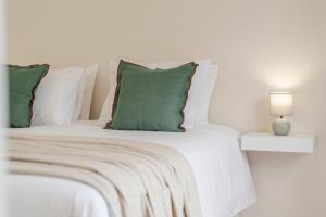 a white bed with green pillows and a lamp at Santa Luzia III by An Island Apart in Funchal