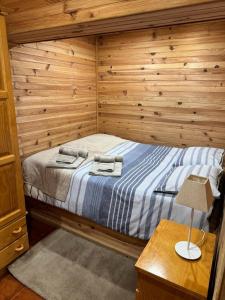 a bedroom with a bed and a wooden wall at Mountain Lodge T3 Duplex Abrigo do Lobo in Covilhã