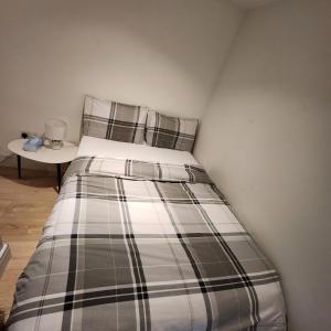a bed in a room with a side table at Nice Apartment Close to Ilford Station , NETFLIX AND WI-FI FREE in Ilford