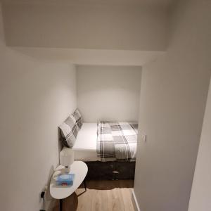 a small bedroom with a bed and a toilet at Nice Apartment Close to Ilford Station , NETFLIX AND WI-FI FREE in Ilford