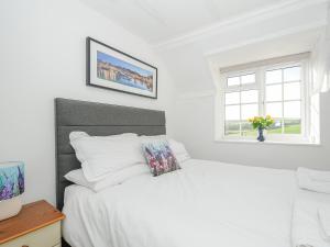 Habitación blanca con cama y ventana en Manor Cottage Barn, en Callington