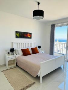 a white bedroom with a bed and a large window at Sliema 2 Bedroom Penthouse in Sliema