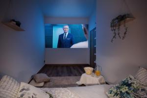 Ein Mann in einem Anzug auf einem Bildschirm in einem Zimmer in der Unterkunft The Forest Apartment - Sauna, Center & Wood in Karlsbad