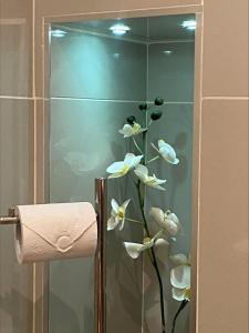 una puerta de ducha de cristal con un jarrón de flores blancas en The DeerView Lodge, en Cardiff