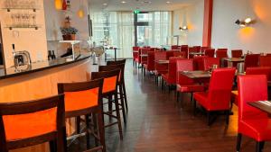 a restaurant with red chairs and a bar at Hotel Rhein-Ruhr Bottrop in Bottrop