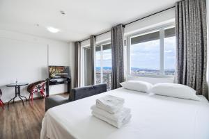 a bedroom with a white bed with a large window at Piscina aquecida Vista Romântica Estacionamento in Osasco