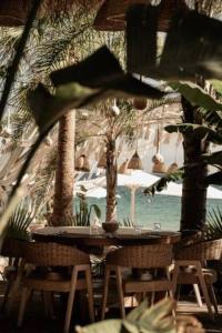 an outdoor table and chairs with palm trees and the ocean at Kohylia by La Scala Beach in Limenas