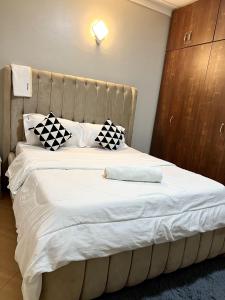 a bedroom with a large white bed with black and white pillows at Cyda Pearl Home-Buziga-Munyonyo in Kampala