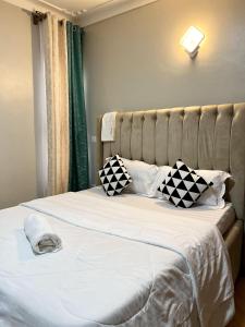 a bed with black and white pillows on it at Cyda Pearl Home-Buziga-Munyonyo in Kampala