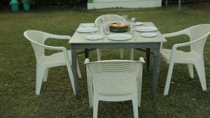 una mesa con sillas blancas y un tazón de comida. en Hill View Resort by Rudrakshi, en Udaipur