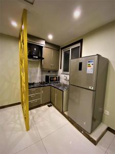 ラホールにある101-NEXT INN Premier Suitesのキッチン(ステンレス製の冷蔵庫、キャビネット付)