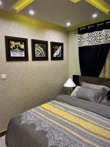 ラホールにある101-NEXT INN Premier Suitesのベッドルーム1室(ベッド2台付)が備わります。壁に3枚の写真が飾られています。