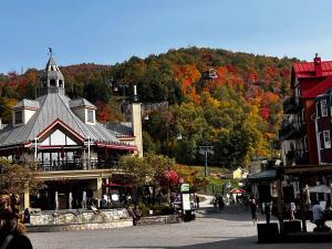 a town with a building with a mountain in the background at Condo du Bonheur in Mont-Tremblant