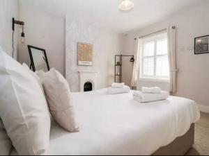 two white beds in a bedroom with a fireplace at Beautiful 4 Bed Beach House - Pool table & Parking in Pakefield