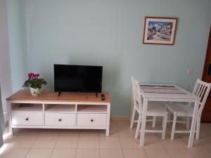 uma sala de estar com uma mesa e uma televisão num armário em Cascada de colores em Los Cancajos