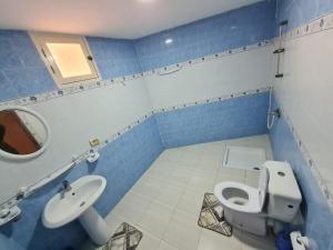 La salle de bains bleue et blanche est pourvue de toilettes et d'un lavabo. dans l'établissement Bienvenue dans votre appartement, à Gabès